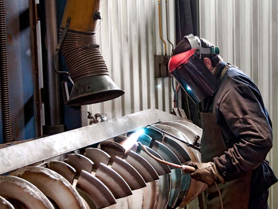 a man welding a piece of metal - Maintenance Préventive